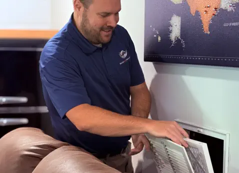 Senior Home Assurance representative changing HVAC return air filter