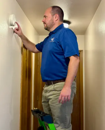 Senior Home Assurance representative testing smoke detector