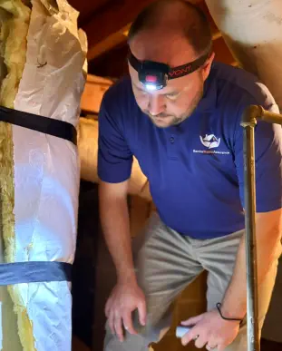 Senior Home Assurance representative lookin for leaks around hot water tank