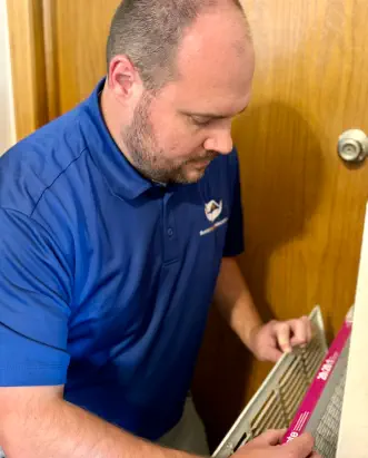 Senior Home Assurance representative changing return air filter